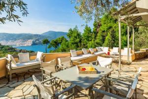 a patio with tables and chairs and a view of the water at Villa Pelago in Skopelos Town