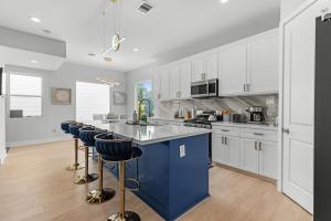 a kitchen with white cabinets and a blue island with bar stools at Villa De Briley in Houston