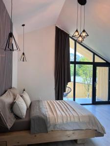 a bedroom with a bed and a large window at Tinutul Luanei Village in Bozioru