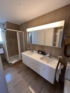 a bathroom with a white sink and a shower at Hotel De la Paix in Lucerne