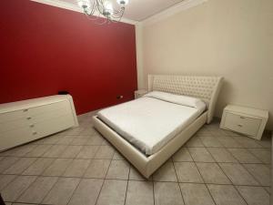 una camera con un letto bianco e una parete rossa di Casa vacanze a Scoglitti