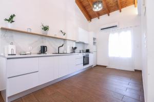a kitchen with white cabinets and a wooden floor at Casa San Pierro in Corfu