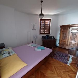 a bedroom with a large bed and a wooden floor at Old Town Arbia in Rab
