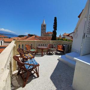 a patio with chairs and tables on a balcony at Old Town Arbia in Rab