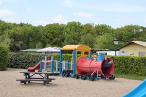 ein Kind reitet auf einem Spielplatz auf einem Zug in der Unterkunft Holiday park Duinhoeve in Udenhout