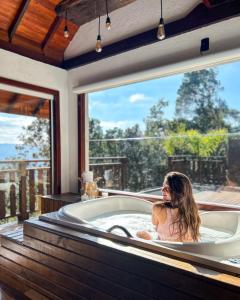 a woman in a bath tub in a room with a window at Recanto das Cachoeiras in Angelina