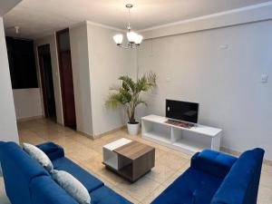 a living room with a blue couch and a tv at Depa. Acogedor centro histórico in Ayacucho