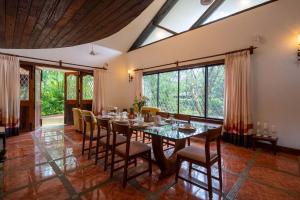 a dining room with a table and chairs and windows at StayVista at Gulmohar Gardens with Gazebo, BBQ in Lonavala