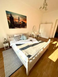 1 dormitorio con 1 cama blanca y una pintura en la pared en TOP lokalita u Pražského hradu! en Praga