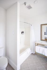 a white bathroom with a tub and a toilet at Hotel Callista in Norwich