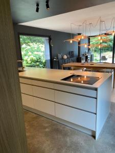 a kitchen with a white counter and a large window at Les koumouls Grange noire in Gouesnou +6 photos