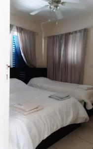 a bedroom with two beds with white sheets and a window at Efterpis12 St. House in Paralimni