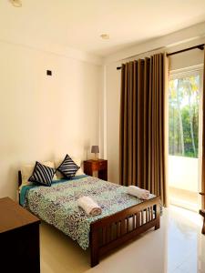 a bedroom with a bed and a large window at Villa Avi - Near Airport in Negombo