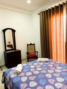 a bedroom with a bed and a mirror and a chair at Villa Avi - Near Airport in Negombo