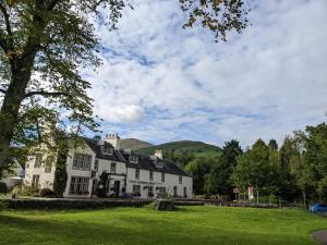 ein weißes Haus mit einem Hügel im Hintergrund in der Unterkunft Heather Cottage Luss in Luss