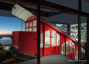 a red train inside of a building with windows at Bürgenstock Hotel & Alpine Spa in Bürgenstock