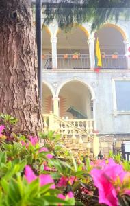 un edificio con un albero e fiori rosa di fronte di Old House Korolistavi a Batumi