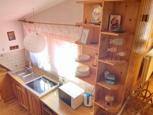 eine Küche mit einem Waschbecken und einer Theke mit Holzregalen in der Unterkunft Dunaparti fészek a Dunakanyarban in Pilismarót