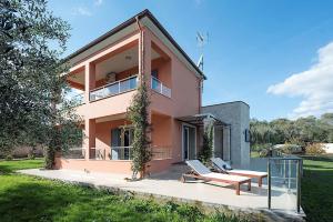 une maison rose avec 2 chaises sur une terrasse dans l'établissement Contemporary Corfu Retreat - 3 Bedrooms - Villa Girasole - Artful Decor - Lush Garden - Tranquil Setting, à Dafnila