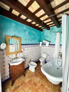 a bathroom with two toilets and a tub and a sink at Hotel Servilia in Carmona