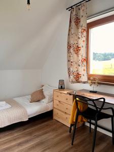 a bedroom with a desk and a bed and a window at Zagroda wypoczynkowa- Domki nad rzeką in Smerekowiec