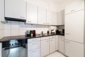 uma cozinha branca com armários brancos e um lavatório em Maraini 8 by Quokka 360 - comfort close to the station em Lugano