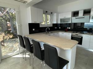 eine Küche mit einer Insel mit schwarzen Stühlen drum herum in der Unterkunft RIZARIA sea view house in Spartýlas