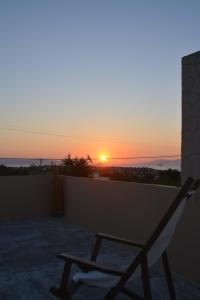 a chair on a balcony with the sunset in the background at Lily's studio in Vathí