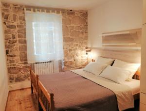 1 dormitorio con 1 cama grande y pared de piedra en Apartment Julija, en Vodice
