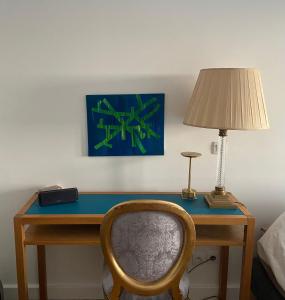 a desk with a lamp and a chair in a room at Grand appartement luxueux, calme et sûr in Paris