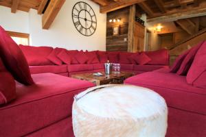 a living room with red couches and a clock on the wall at Charming Chalet w/ Mountain & Slope Views, Jacuzzi in Vars