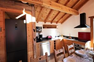 eine Küche mit Holzschränken und einem schwarzen Kühlschrank in der Unterkunft Charming Chalet w/ Mountain & Slope Views, Jacuzzi in Vars