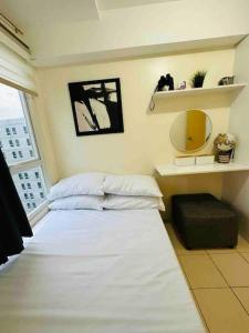 Condo in Ortigas (Kimea Suite) في مانيلا: غرفة نوم بسرير ابيض ومرآة