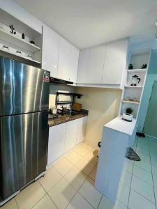 a kitchen with a stainless steel refrigerator and white cabinets at Condo in Ortigas (Kimea Suite) in Manila