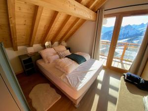 a bed in a room with a large window at Chalet La Mahure in La Toussuire