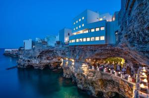 a building on a cliff next to the water at night at Le terrazze di Rosa in Polignano a Mare