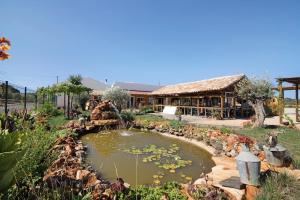 einem Teich inmitten eines Gartens mit einem Gebäude in der Unterkunft Casa de Aloe in Paderne