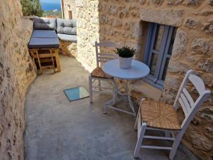 eine Terrasse mit einem Tisch und Stühlen an einer Steinmauer in der Unterkunft Marianta house in Areopoli