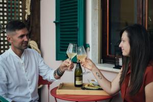 un hombre y una mujer sosteniendo copas de vino blanco en La Piccola Lady, en La Spezia