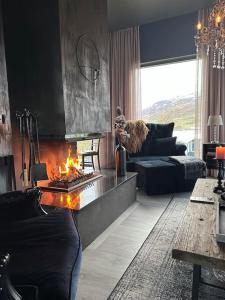 sala de estar con chimenea y sofá en Black pearl - Villa with a view, en Grenivík