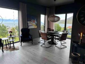 una sala da pranzo con tavolo, sedie e ampie finestre di Black pearl - Villa with a view a Grenivík