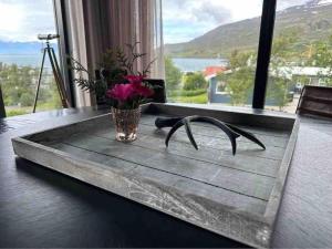 uma bandeja de madeira com um vaso de flores sobre uma mesa em Black pearl - Villa with a view em Grenivík