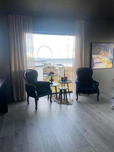 uma sala de estar com duas cadeiras e uma mesa e uma grande janela em Black pearl - Villa with a view em Grenivík