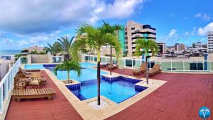 a rooftop pool with benches and palm trees on a building at Vacanze - Austrália (JTR) in Maceió