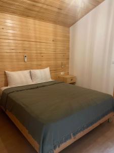 1 dormitorio con 1 cama con pared de madera en ALANYA BUNGALOW EVLERİ / RESTAURANT en Asmaca