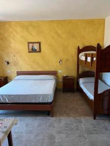 1 dormitorio con 2 literas y pared amarilla en Aquila D'oro, en Cirò