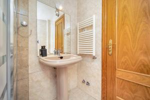 uma casa de banho com um lavatório e um chuveiro com um espelho. em Casa Grande CASA CAFE MADRID 22 PERSONAS em Pozuelo de Alarcón