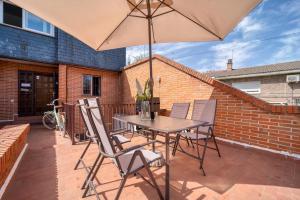 einen Tisch und Stühle mit Sonnenschirm auf einer Terrasse in der Unterkunft Casa Grande CASA CAFE MADRID 22 PERSONAS in Pozuelo de Alarcón