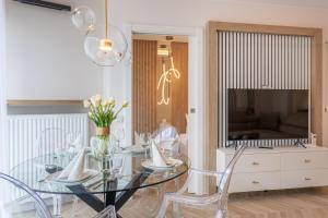 a dining room with a glass table and a television at Apartpark - Ambria Apartments in Świnoujście