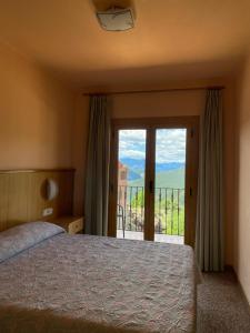 a bedroom with a bed and a balcony at Hostal Alt Llobregat in Castellar de NʼHug